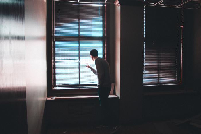 Man looking at the window behind curtains