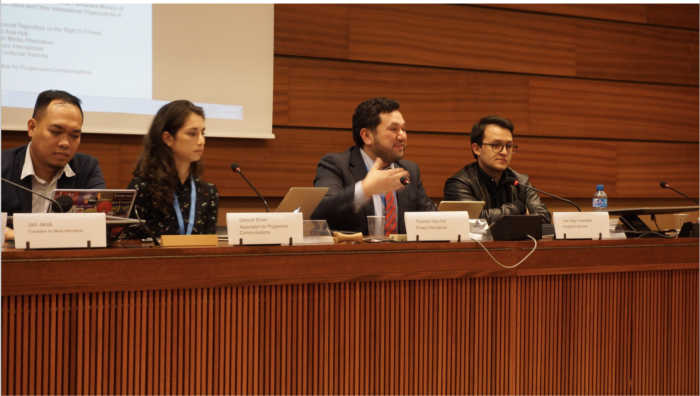 Four people sitting behind a desk in a conference room