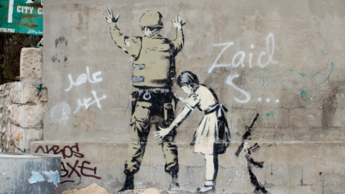 Banksy graffiti on the west Wall of Bethlehem, of a child frisking an armed soldier