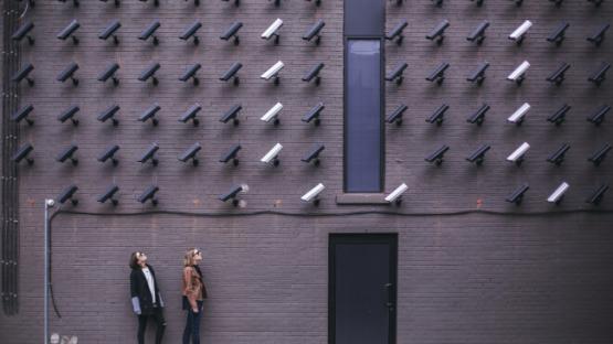 two women looking at surveillance camera art installation