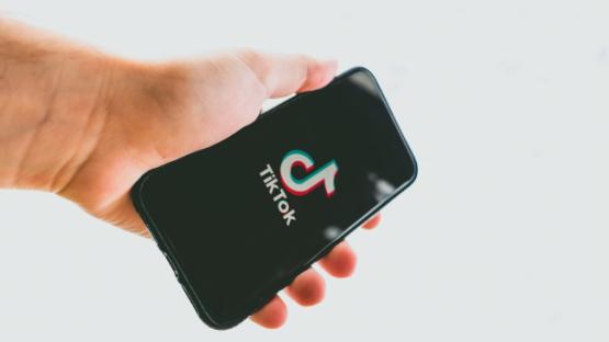 Hand holding a phone with TikTok logo