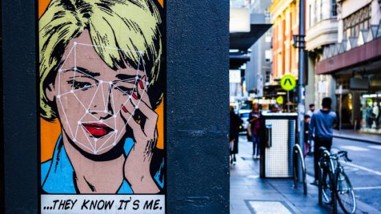 Street art portrait on a wall with a caption "they know it's me"