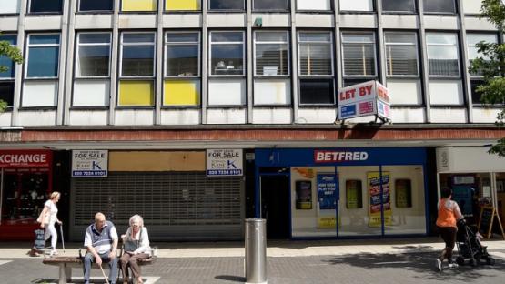 Couple sitting in front of shops in the UK