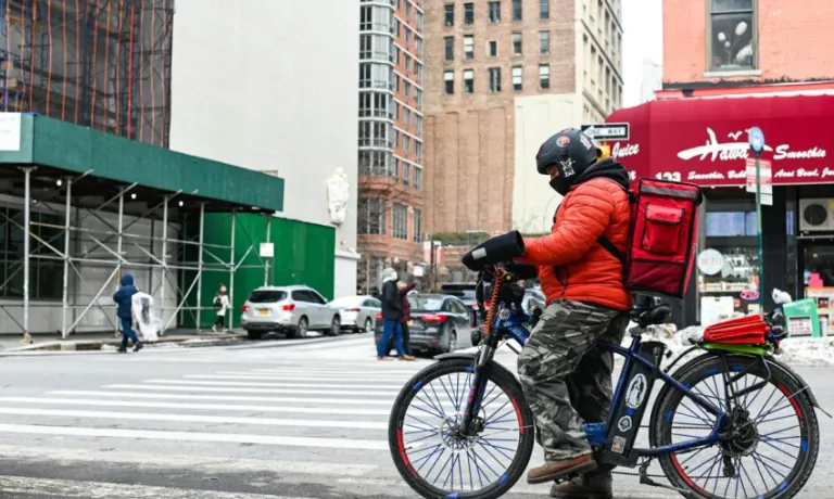 Person on a bike with delivery backpack on a busy city street