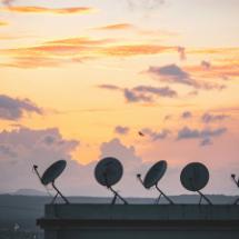 Satellite dishes against sunset background