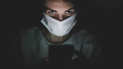 person wearing face mask looking at phone