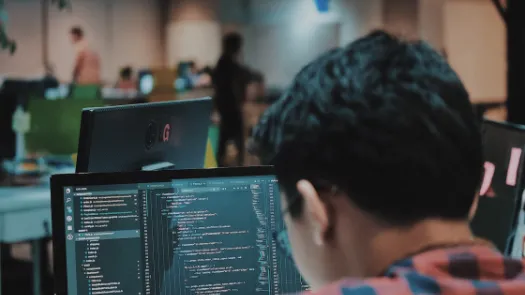 Man back to camera facing a screen with code in an open space