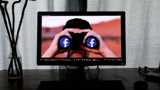 PC monitor showing individual with binoculars with Facebook image