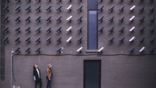 two women looking at surveillance camera art installation