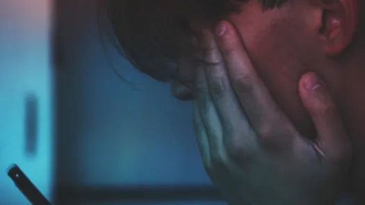 A woman with a hand on her face while watching her phone