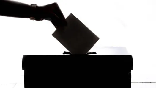 Hand submitting voting ballot into box