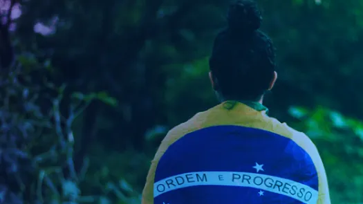 Somone draped in a Brazilian flag, the motto from the center of the Brazilian flag "Ordem e Progresso" or Order and Progress is visible 