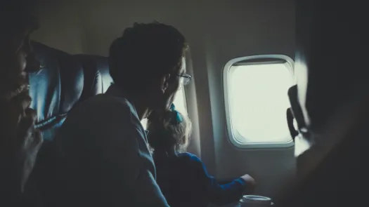 Man and girl looking out airplane window