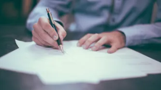 Man writting on paper on a desk