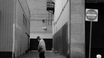 Man walking past alley in black and white