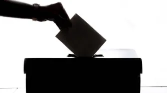 Hand submitting voting ballot into box