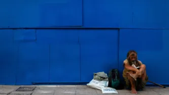 Homeless man sitting on pavement.