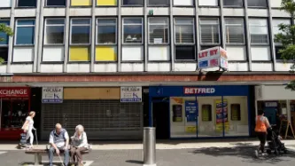 Couple sitting in front of shops in the UK